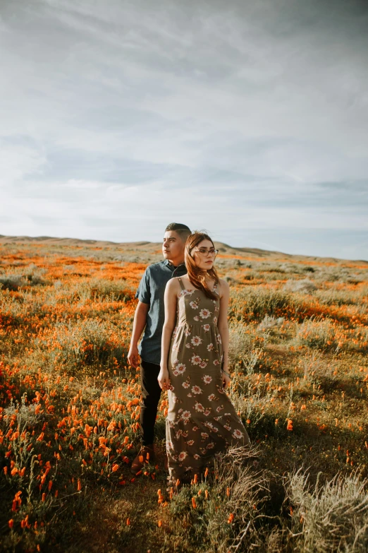 a couple posing for a picture in an open field of flowers