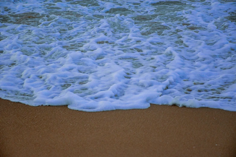 waves crashing into the beach as seen from a high angle