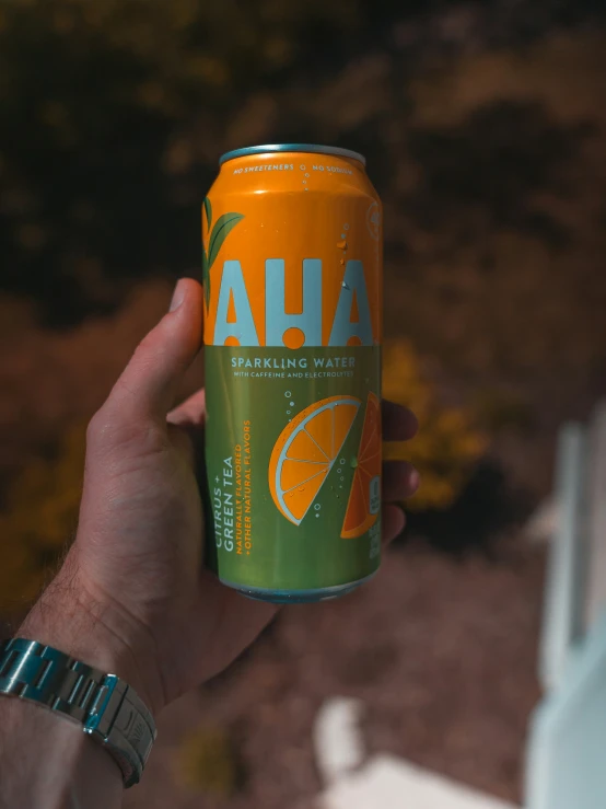 a hand holding an orange and lime soda