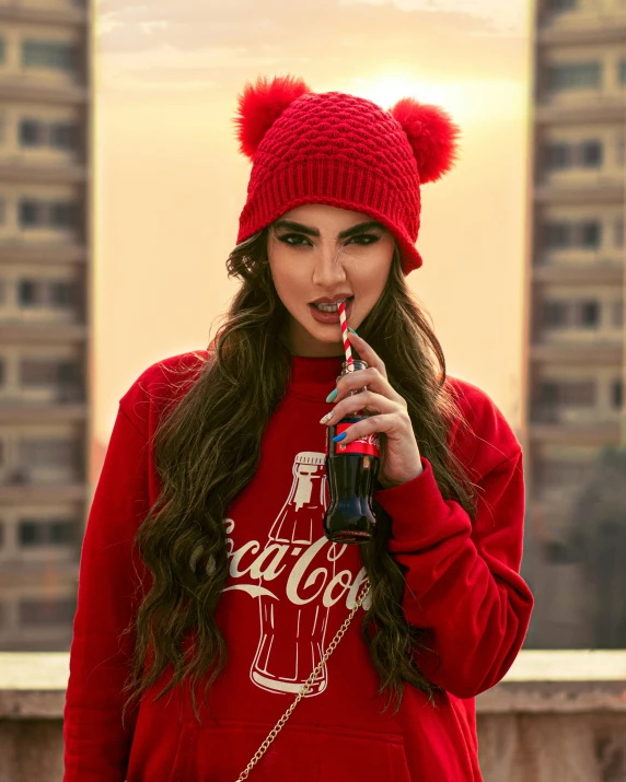 a girl in red holding a soda and drinking soda