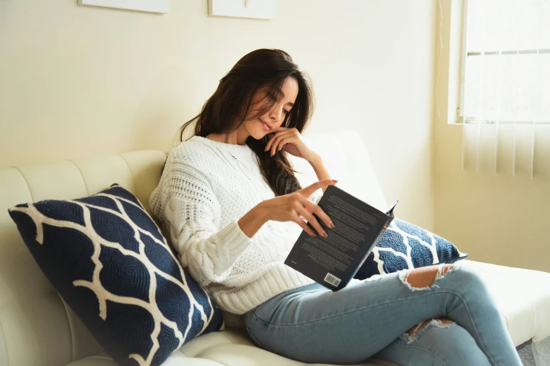 woman sitting on white sofa reading a magazine