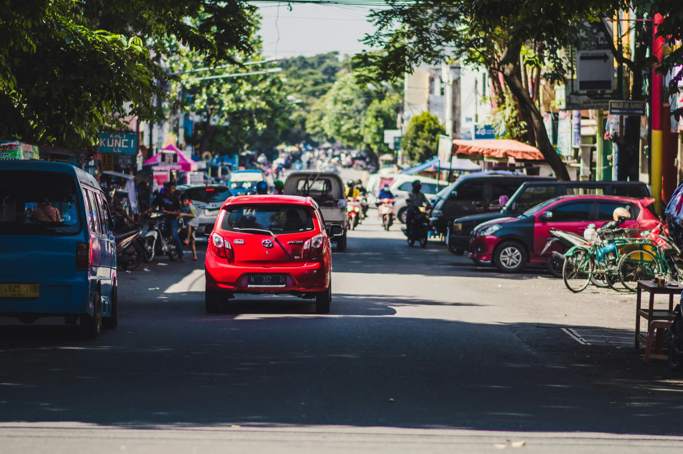 a small red car is driving down the street