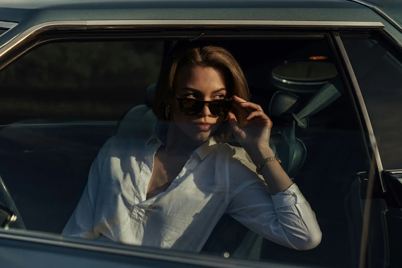 woman with sunglasses on driving in the back of a car