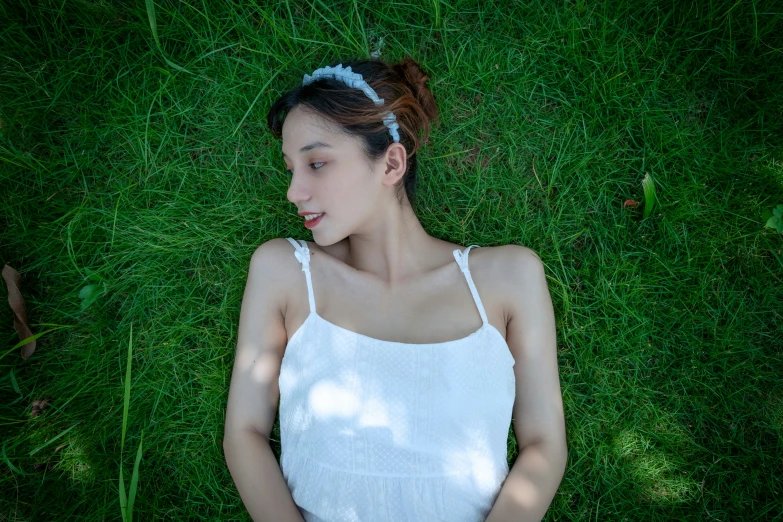 woman in white dress laying on grass looking down