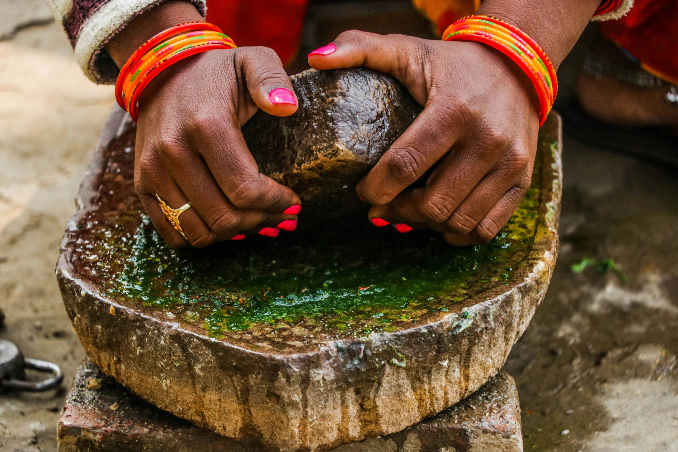 woman using brightly colored celets on green water fountain