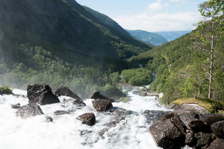 a stream running between some lush green mountains