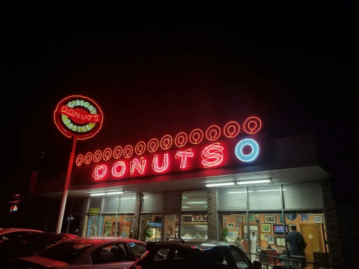 the neon sign for donuts on the side of a building