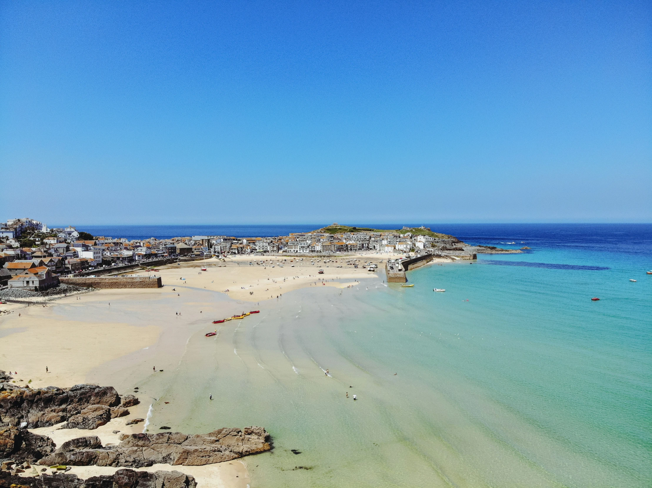 an ocean beach with many boats and people