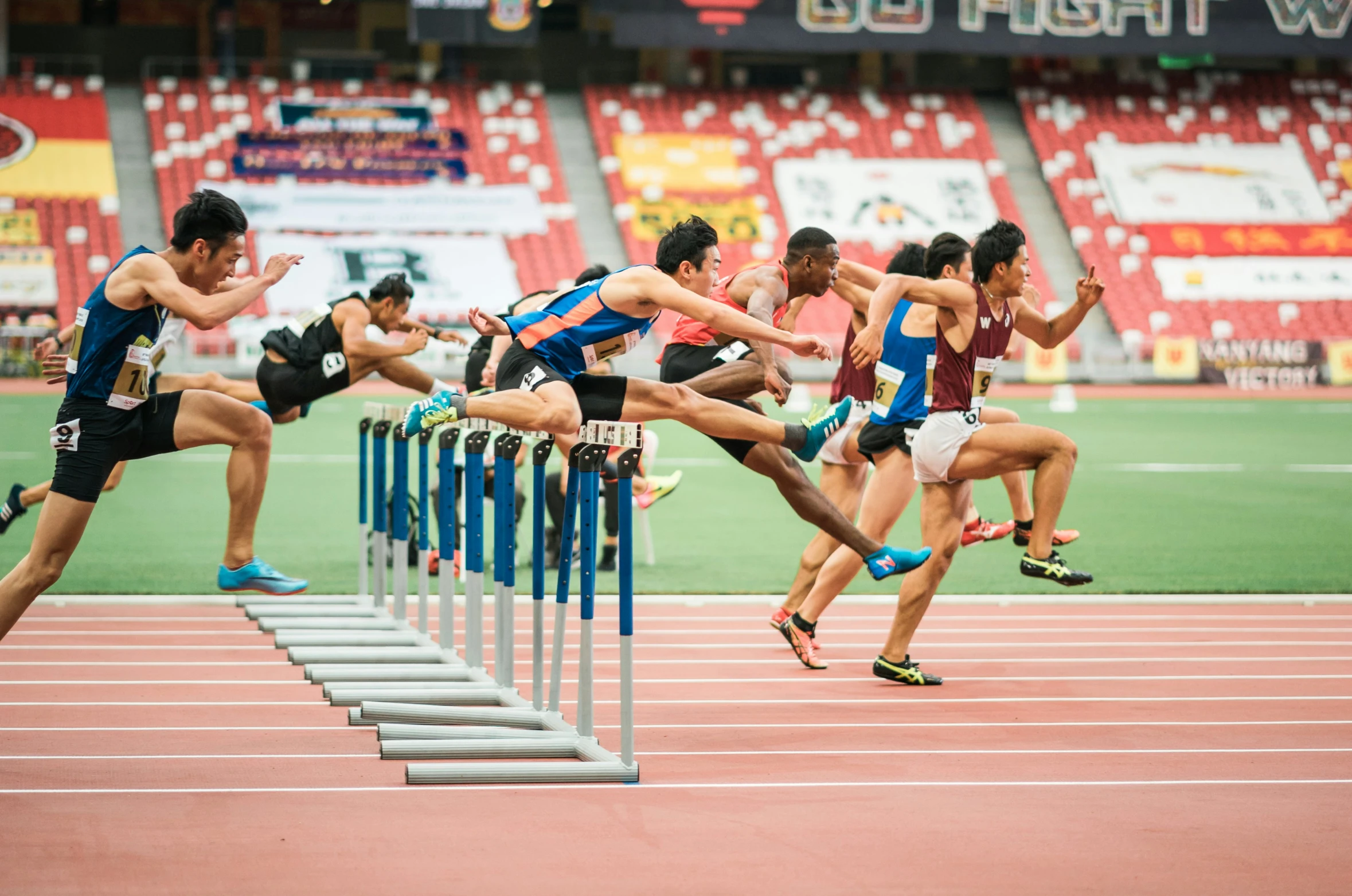 some people are jumping over a hurdle on a track