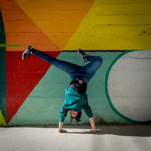 a woman doing handstand in front of a graffiti wall