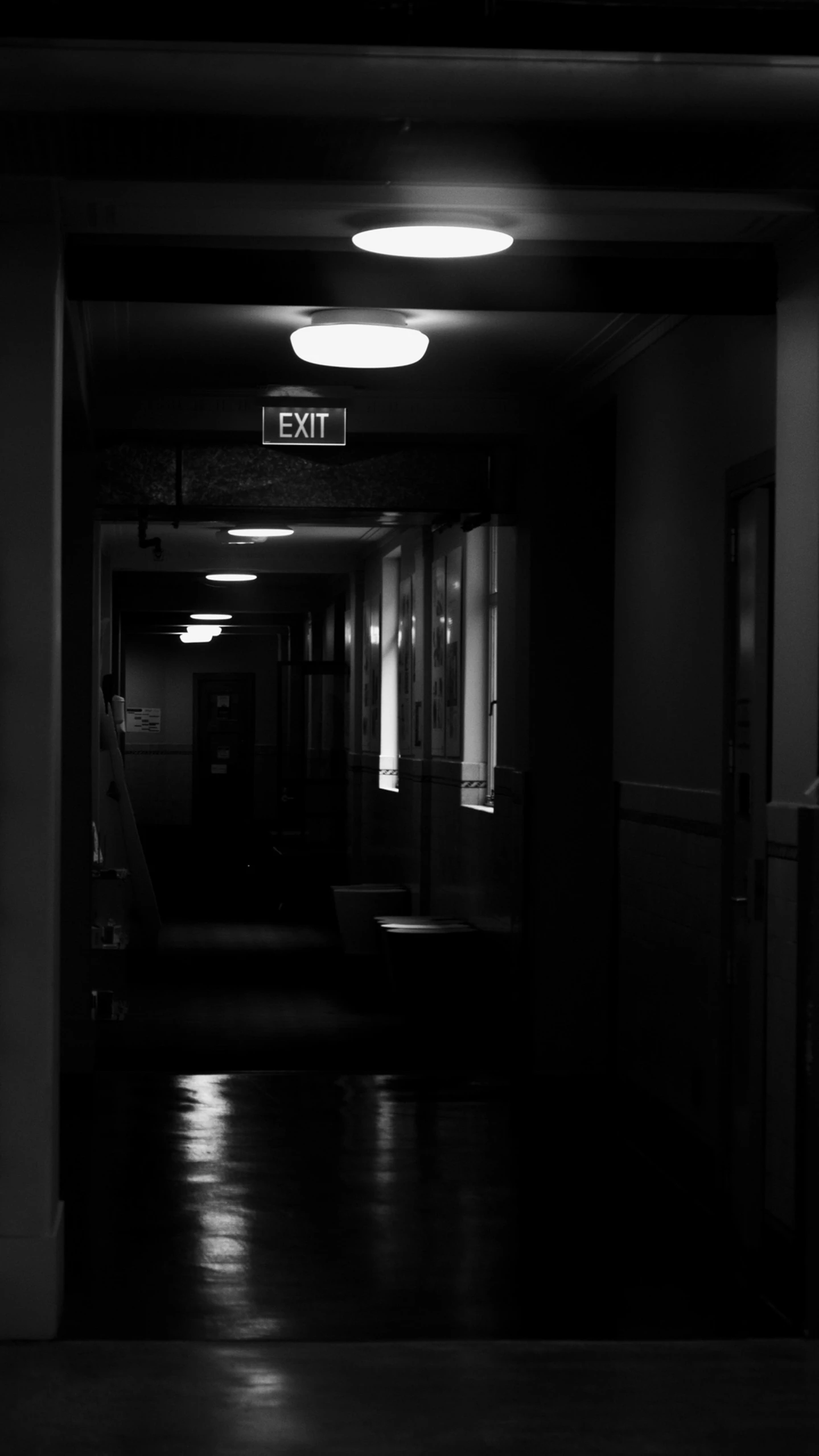 a dimly lit hallway leads to exit lights