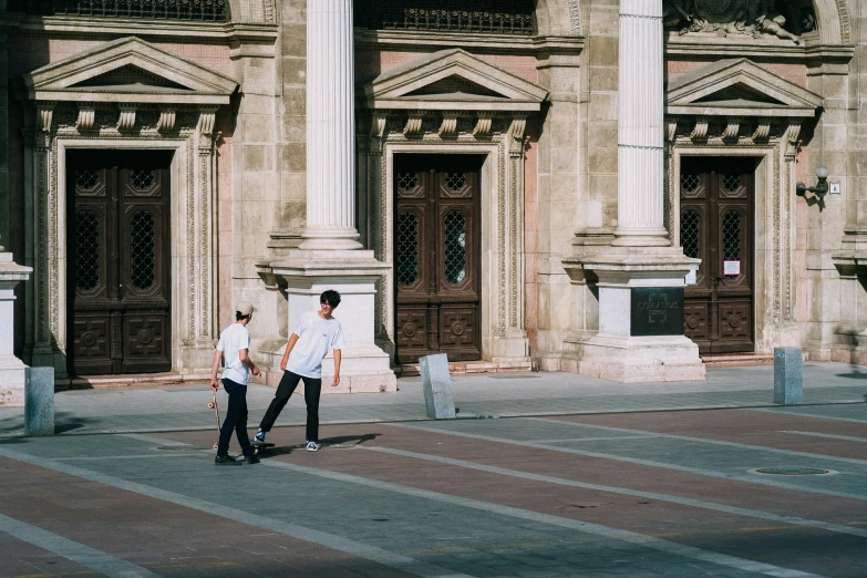 two men stand on the pavement while talking