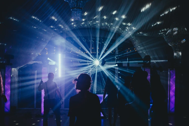 people standing in front of stage lights in a dark room