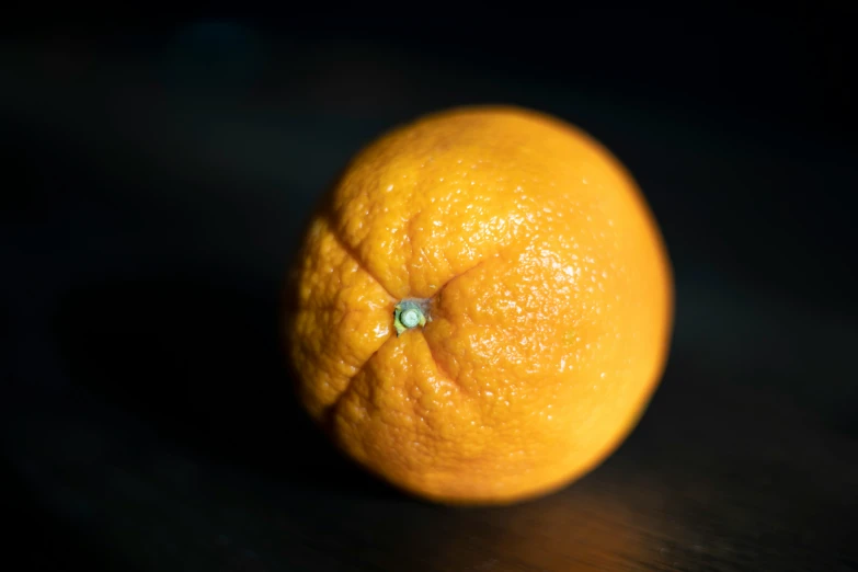 an orange laying on a black surface