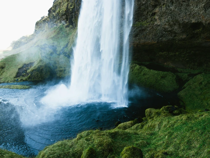 a waterfall and blue water at the end of a cliff