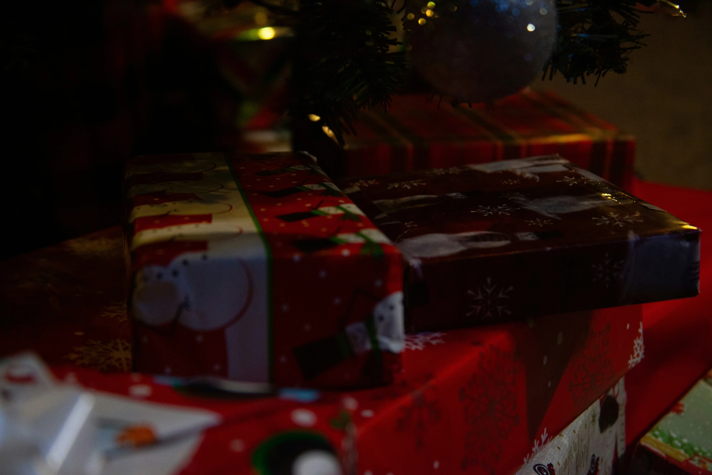 a red wrapped presents sitting on top of a green christmas tree