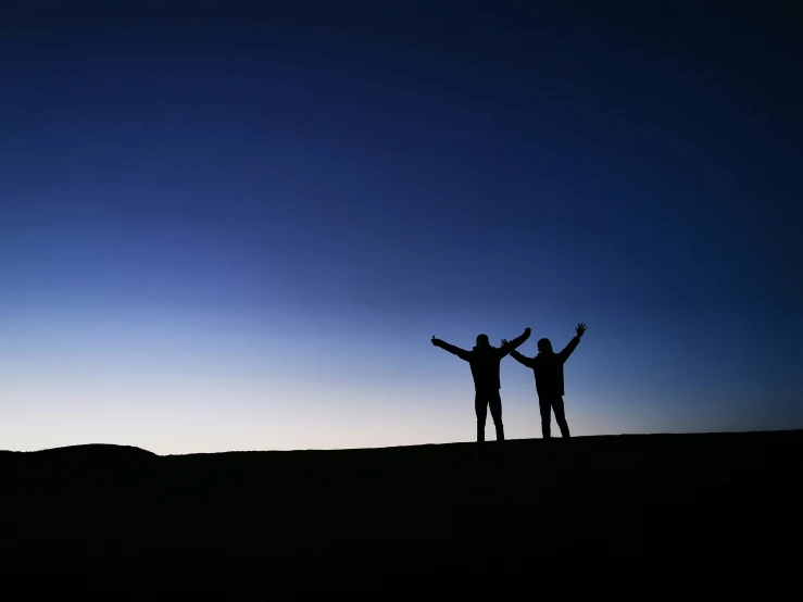 a couple of people standing next to each other on top of a hill