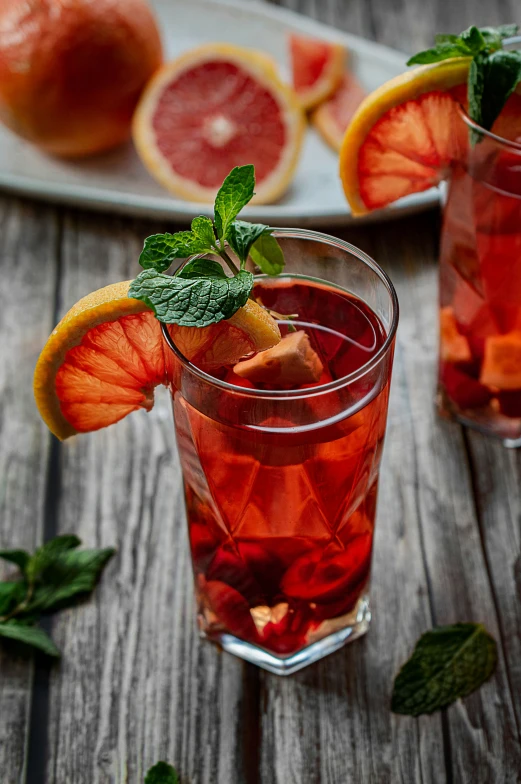 some glasses filled with a drink, a lemon slice and some green leaves