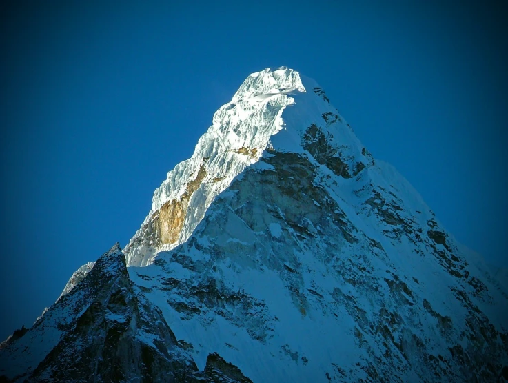 a very large snowy mountain peak with some clouds