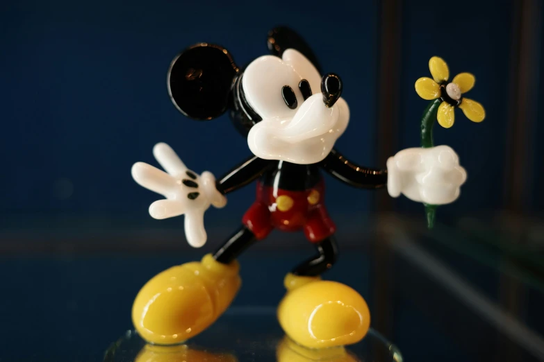a mickey mouse figurine with yellow flowers in its hands