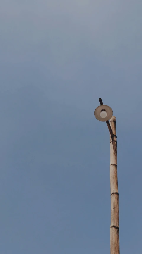 an old wooden light pole stands under a bright blue sky