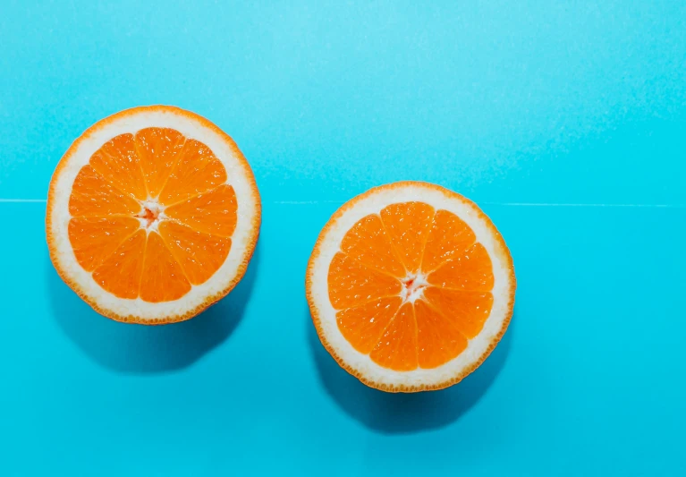 two orange halves sitting next to each other on a blue surface