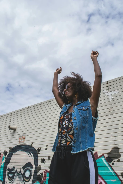 a woman with her arms in the air near a wall