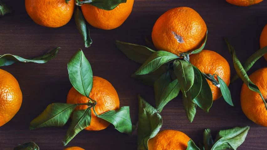 oranges with leaves laid out on the wooden surface