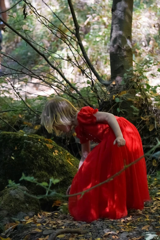 a woman in a long red dress standing in the forest