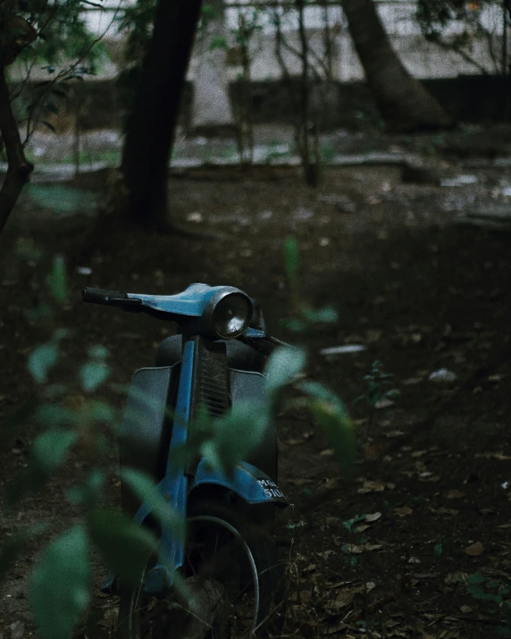 a blue scooter parked in the woods near a building