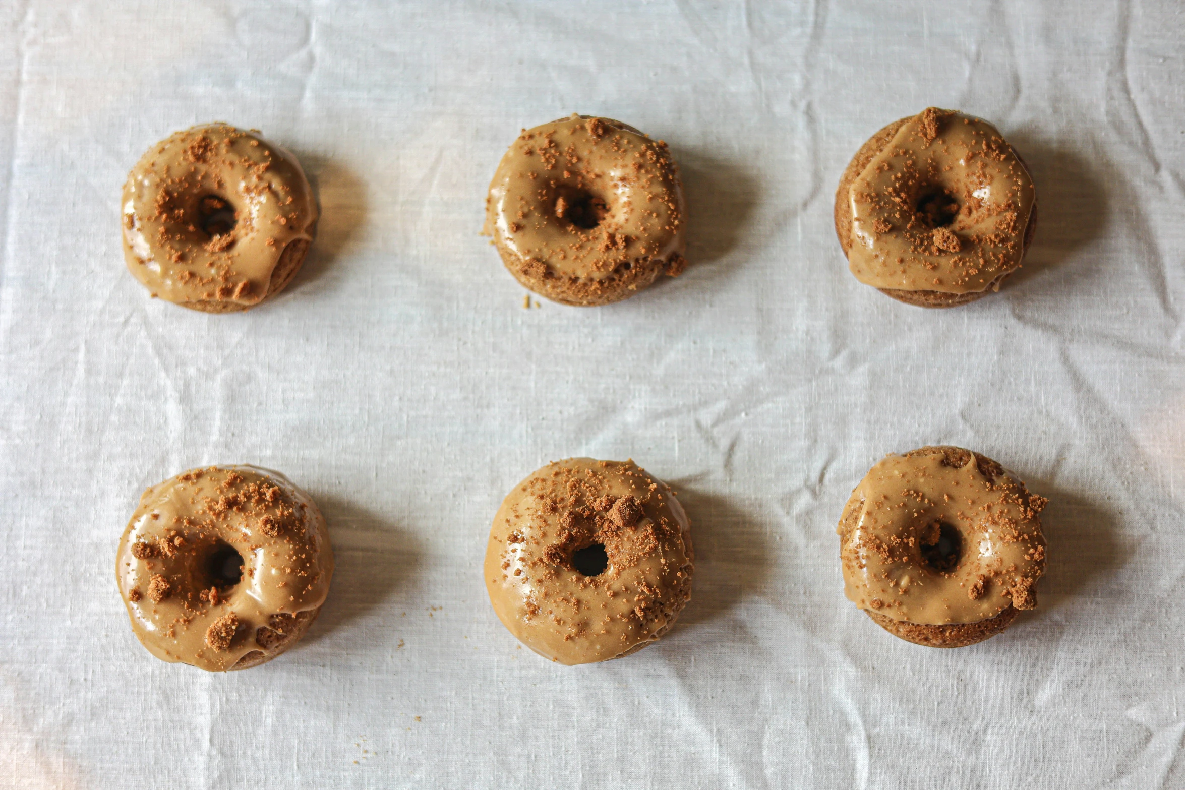 twelve donuts with different toppings placed on a white paper