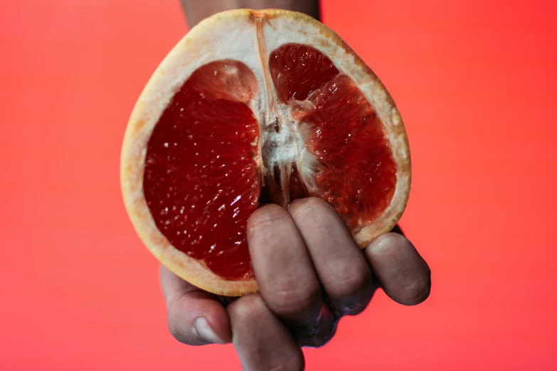 a gfruit half is being held in a person's hands