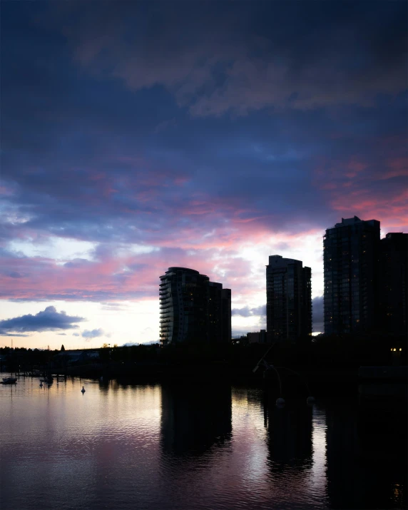 the sun sets over some large buildings and water