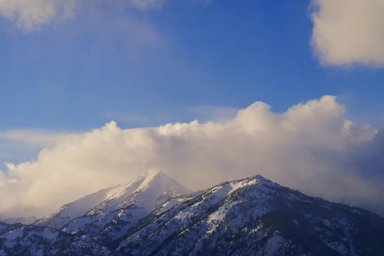 a very tall mountain surrounded by snow covered hills