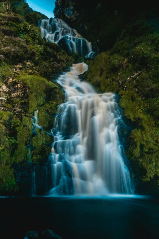 a waterfall is surrounded by rocks and trees