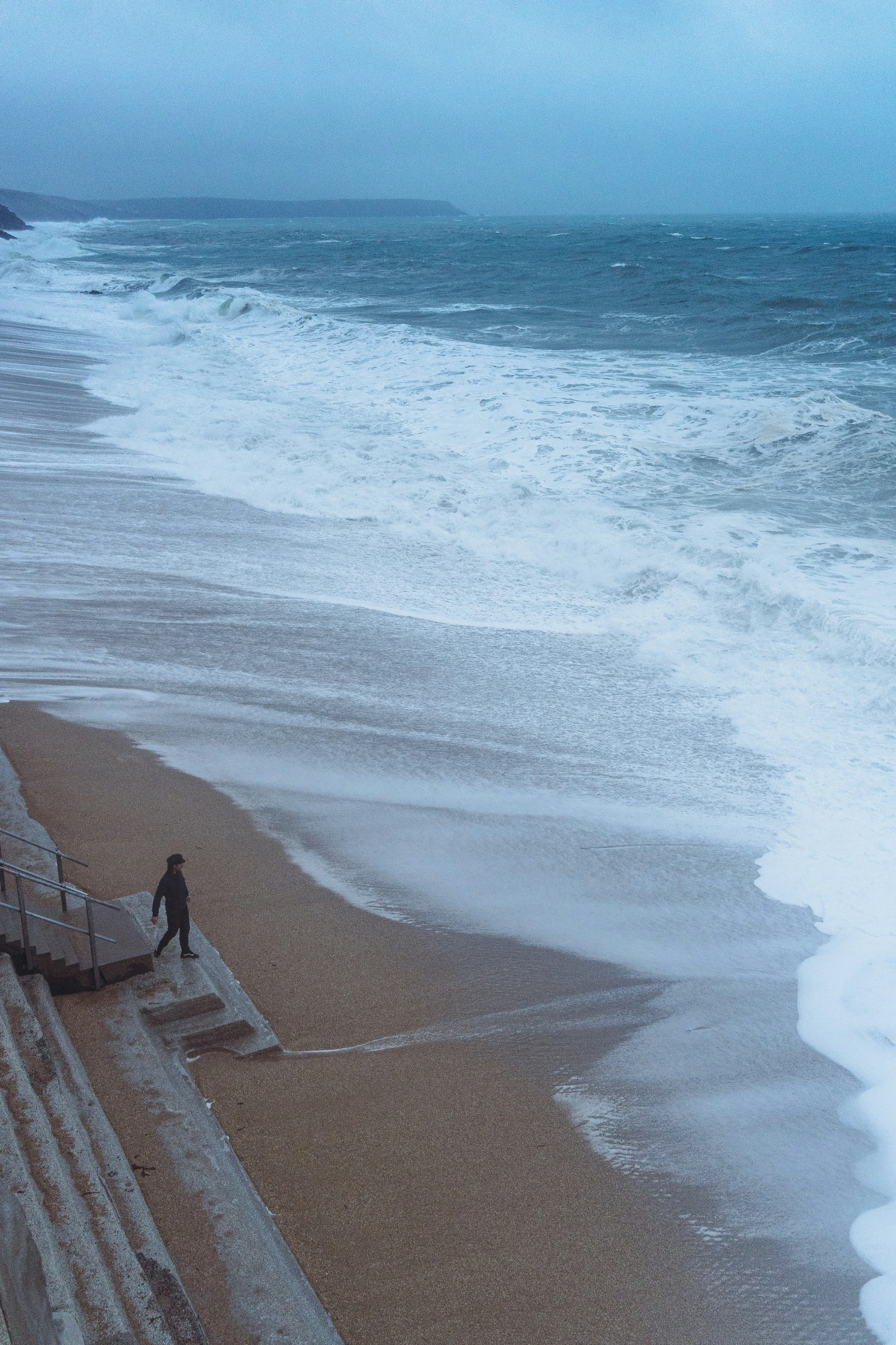 a lone man is walking along the shoreline near the water