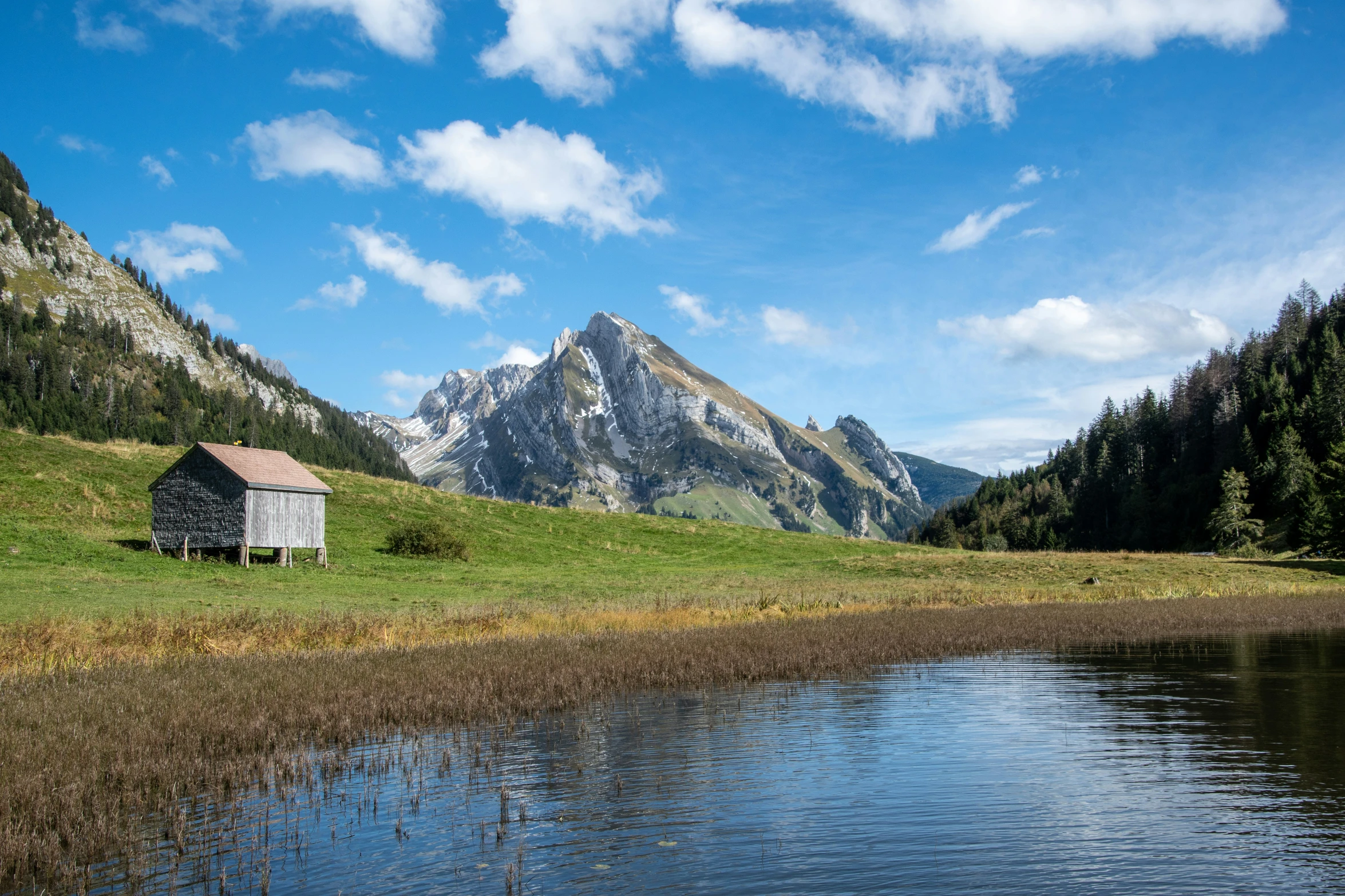 an old abandoned cabin sits alone in a field with mountains