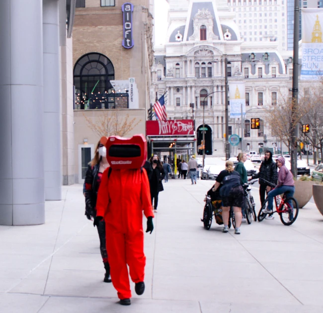 a man in red jumpsuit carrying a box on his back