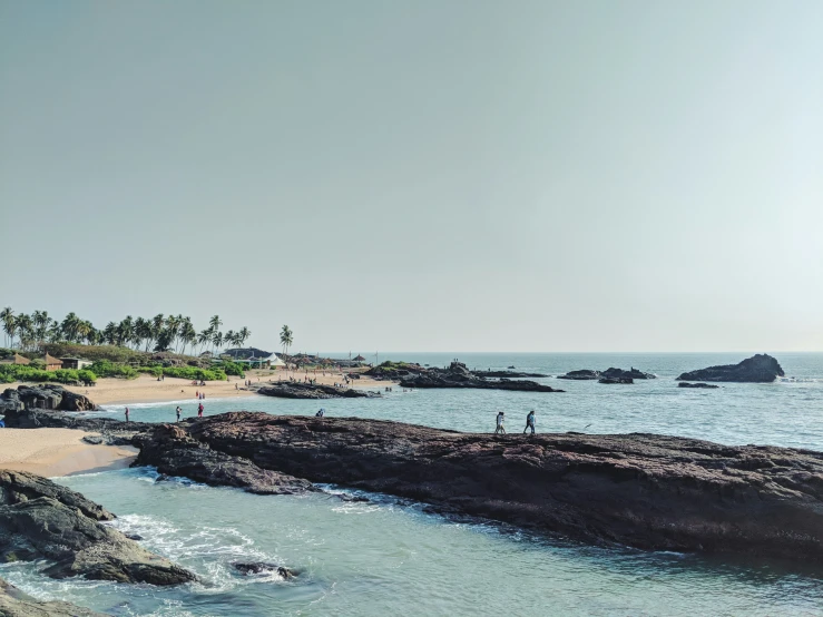 people on the beach next to some rocks