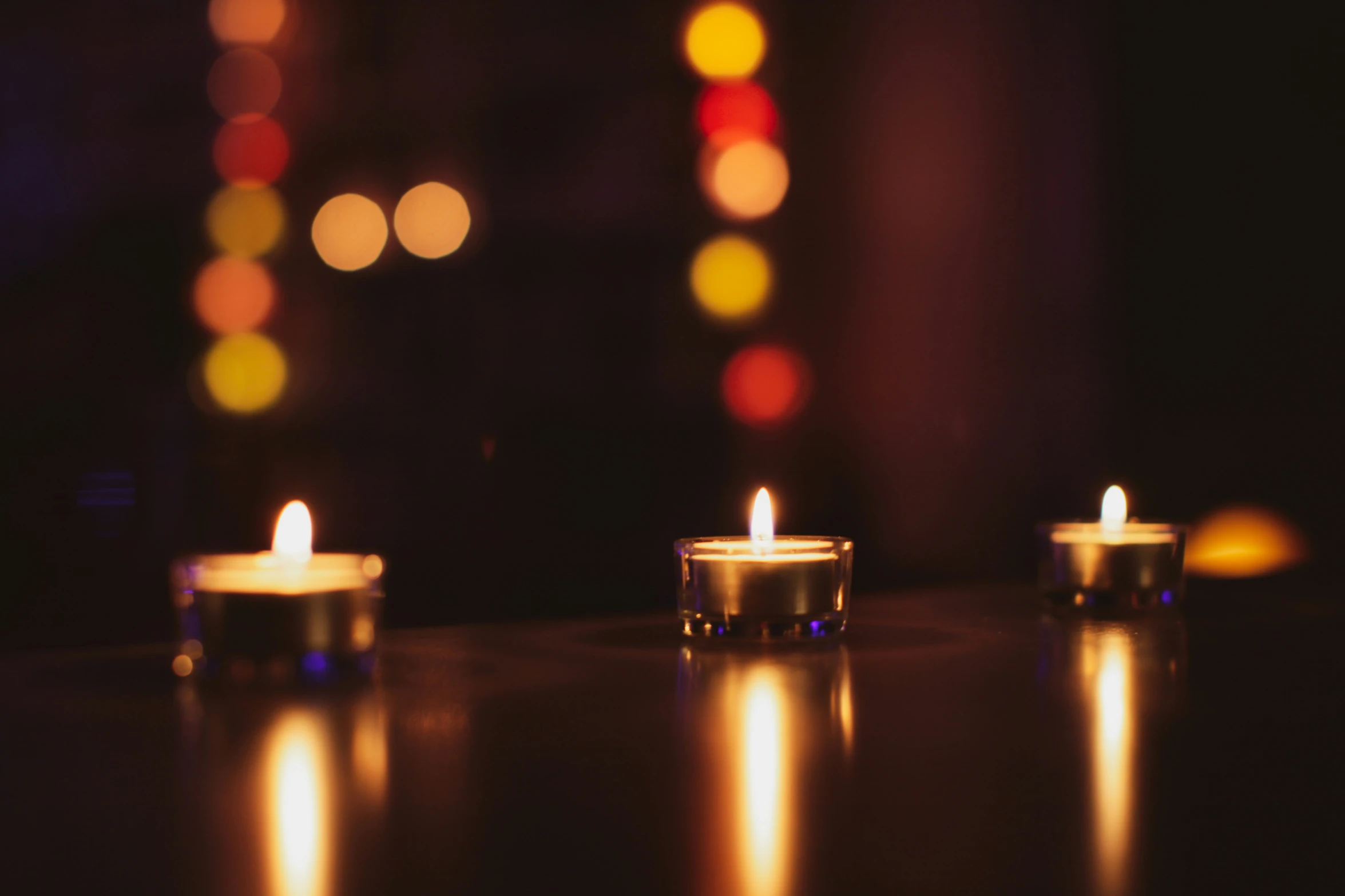 three candles sitting on top of a table in the dark