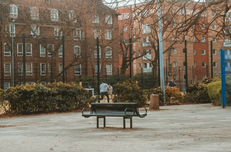 an empty park bench with several people in the background