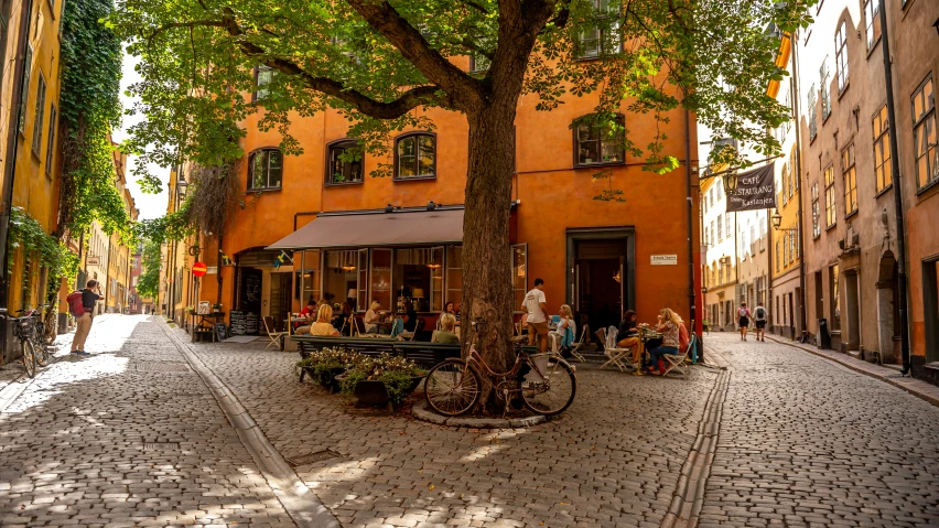 a narrow brick street with people walking by a yellow building