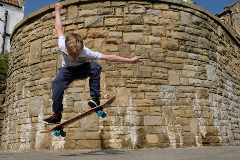 the young man is jumping on his skateboard in front of a brick wall