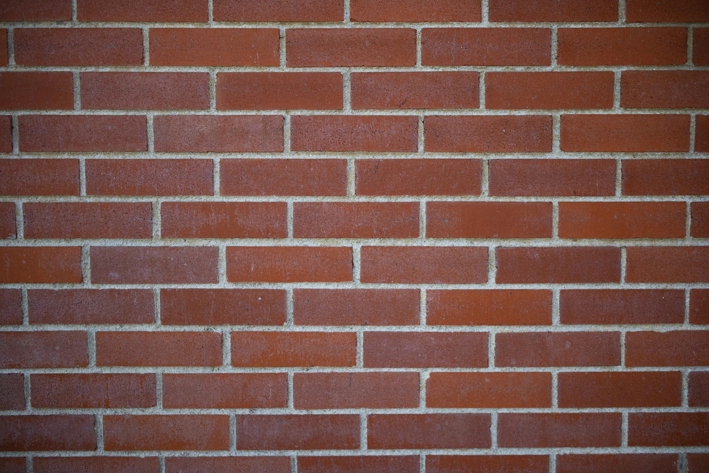 a brick wall with small, thin bricks and light brown grates