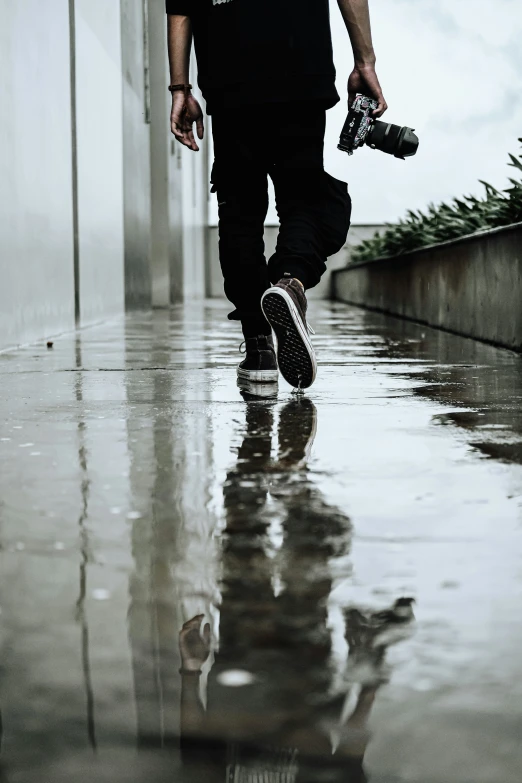 a man with a skateboard walks through an alley