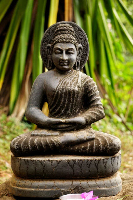 a stone buddha statue sitting in the middle of grass