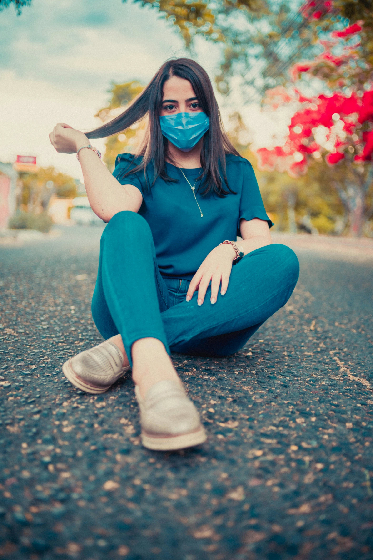 a woman sits on the side of the road while she holds her long hair behind her head