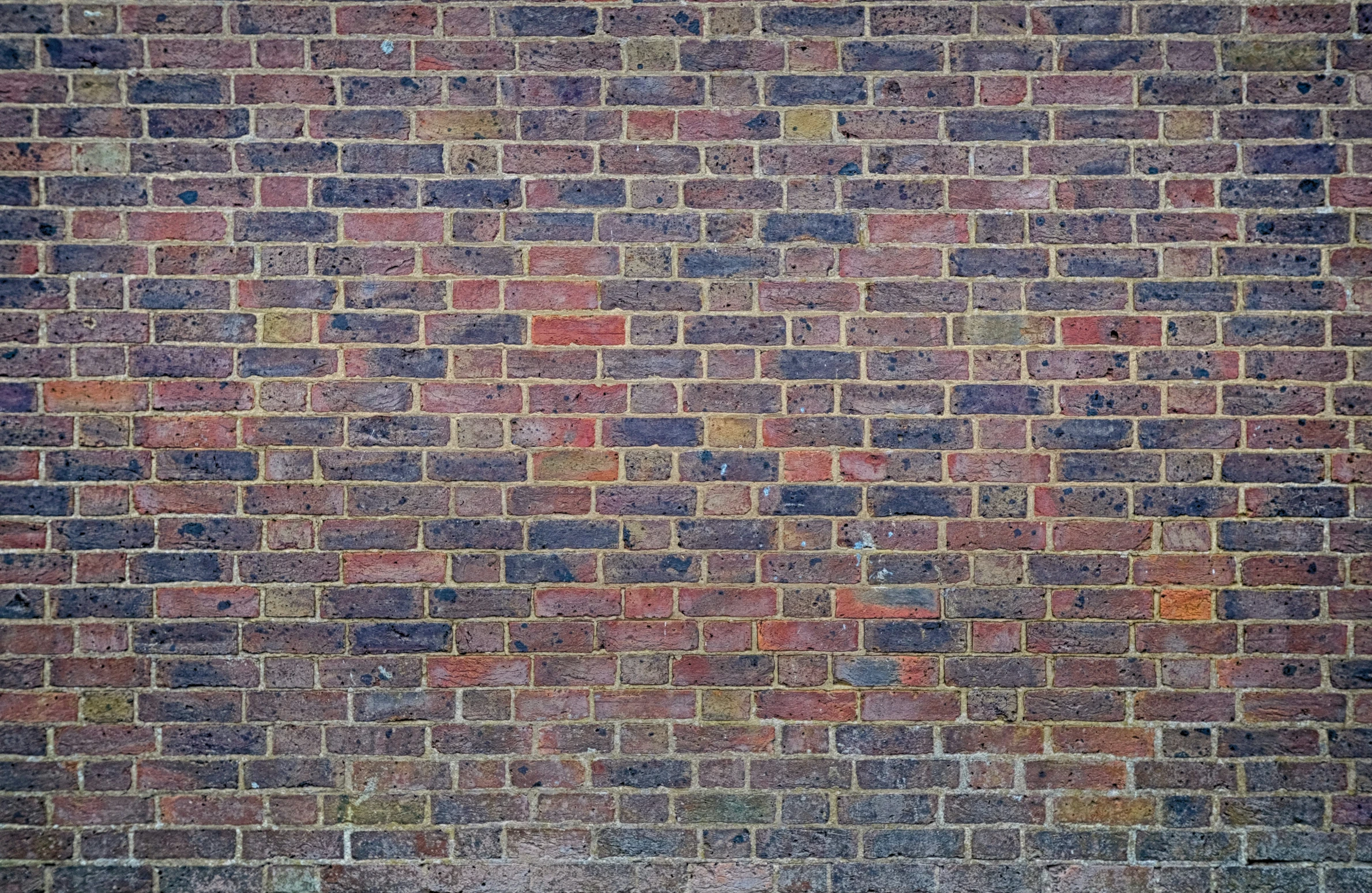 a red brick wall that has a light brown fire hydrant