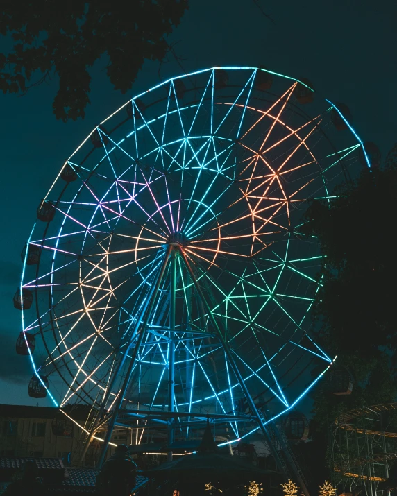 a large wheel illuminated at night in the sky