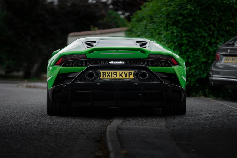 a green sports car parked in front of some trees